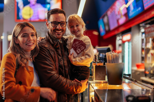 Parents with child buying movie tickets.