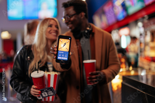 Joyful couple with online app in movie theater.