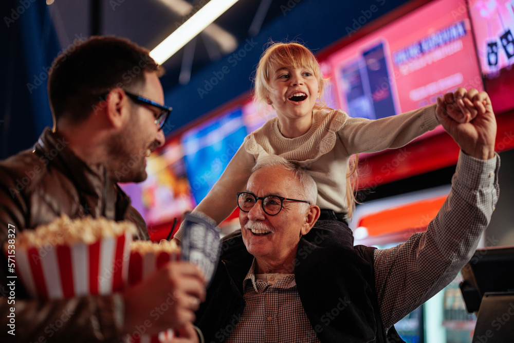 Obraz premium Joyful senior man with son and granddaughter at movies.