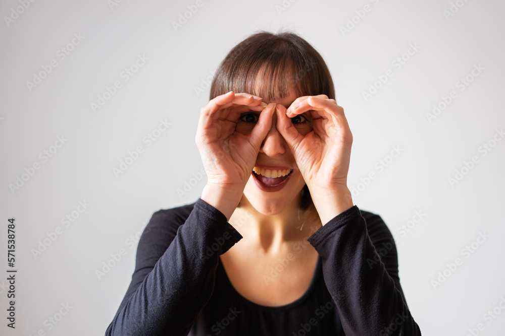 Portrait of a girl on white background. Brown short hair girl. Girl with her hands on her eyes as if they were binoculars Portrait of a girl on white background. Brown short hair girl. Girl with her hands on her eyes as if they were binoculars
