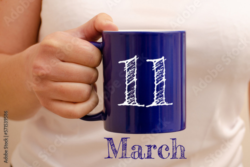 The inscription on the blue cup 11 march. Cup in female hand, business concept