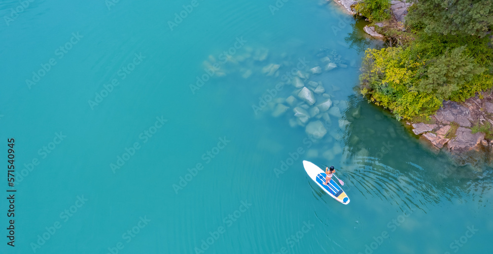 Woman rowing oar on sup board blue sea water. Aerial top view paddleboard banner