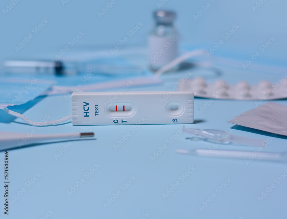 Express hepatitis C virus (HCV) test, Schnelltest, medical mask, syringe,thermometer,medicine on a blue background.The test shows a positive result.Copy space