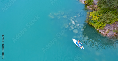 Fototapeta Naklejka Na Ścianę i Meble -  Woman rowing oar on sup board blue sea water. Aerial top view paddleboard banner