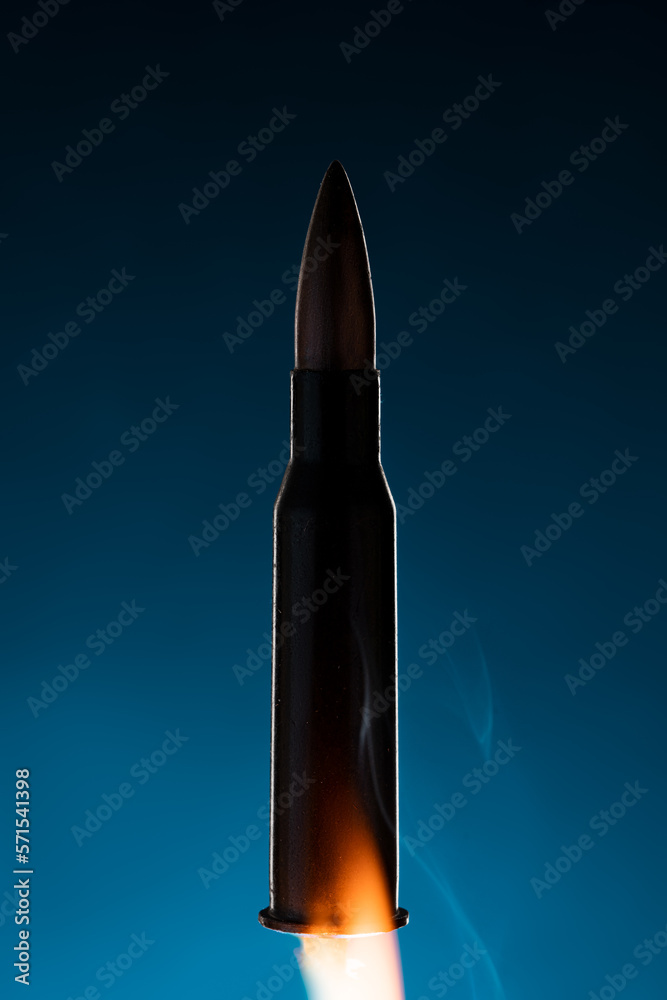 Rifle bullet long cartridge on blue background. Army or hunting weapon shot object, violence and danger symbol. Rifle bullet long cartridge on blue background. Army or hunting weapon shot object, violence and danger symbol.