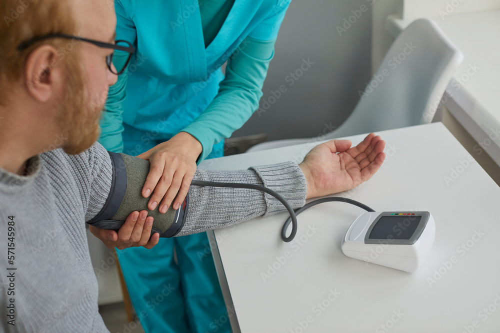 Nurse measure high blood pressure of a sick senior mature male patient in medical clinic closeup. Doctor checking arterial blood pressure of elderly man with hypertension. Healthcare concept. Nurse measure high blood pressure of a sick senior mature male patient in medical clinic closeup. Doctor checking arterial blood pressure of elderly man with hypertension. Healthcare concept.