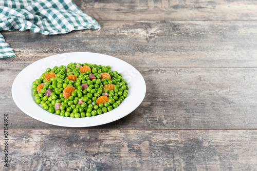 Green peas with serrano ham and carrot on wooden table. Copy space