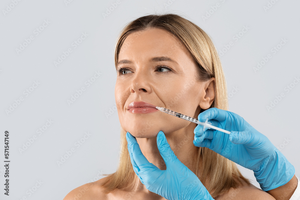 Middle aged woman gets cosmetic injection in her lips, clpseup Middle aged woman gets cosmetic injection in her lips, clpseup