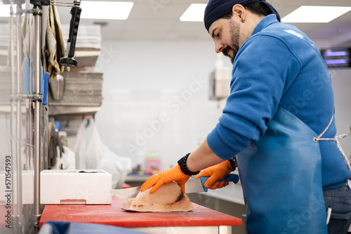 Quadro su tela A uniformed middle-aged fishmonger is slicing a swordfish, selling food, a concept of small and medium-sized businesses