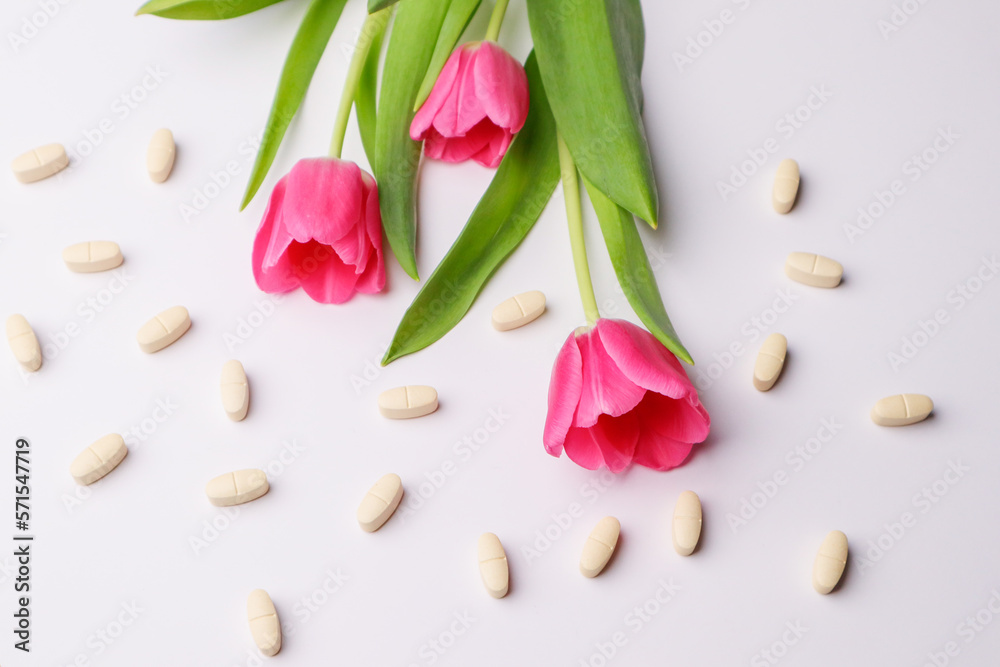 Vitamins pills on a white background and tulips