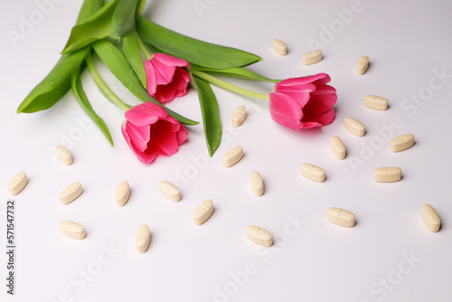 Vitamins pills on a white background and tulips