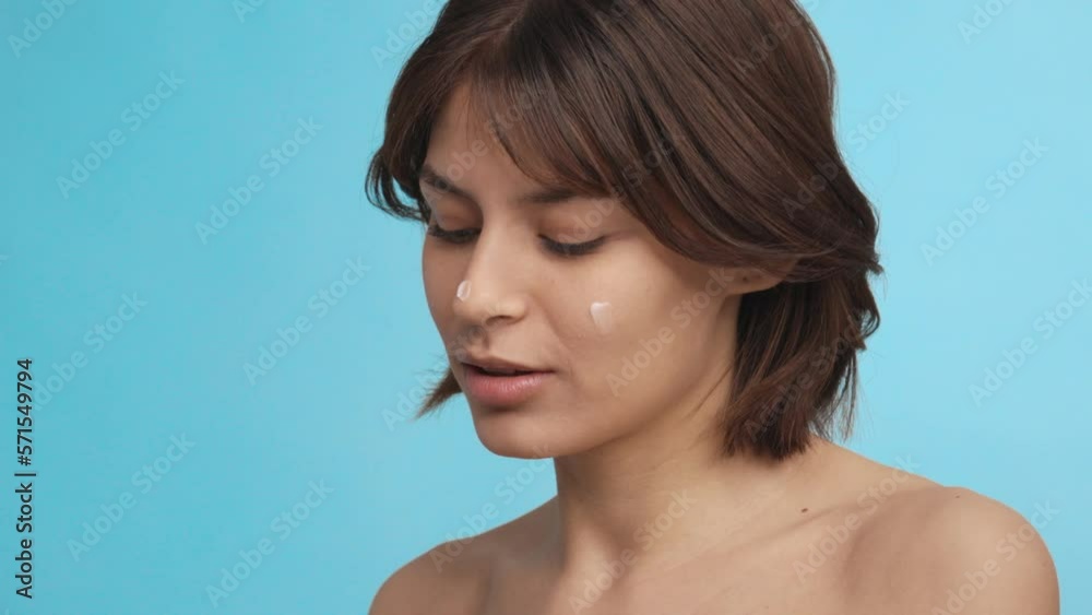 Close-up of a young woman with perfect skin applying cream on her face Close-up of a young woman with perfect skin applying cream on her face