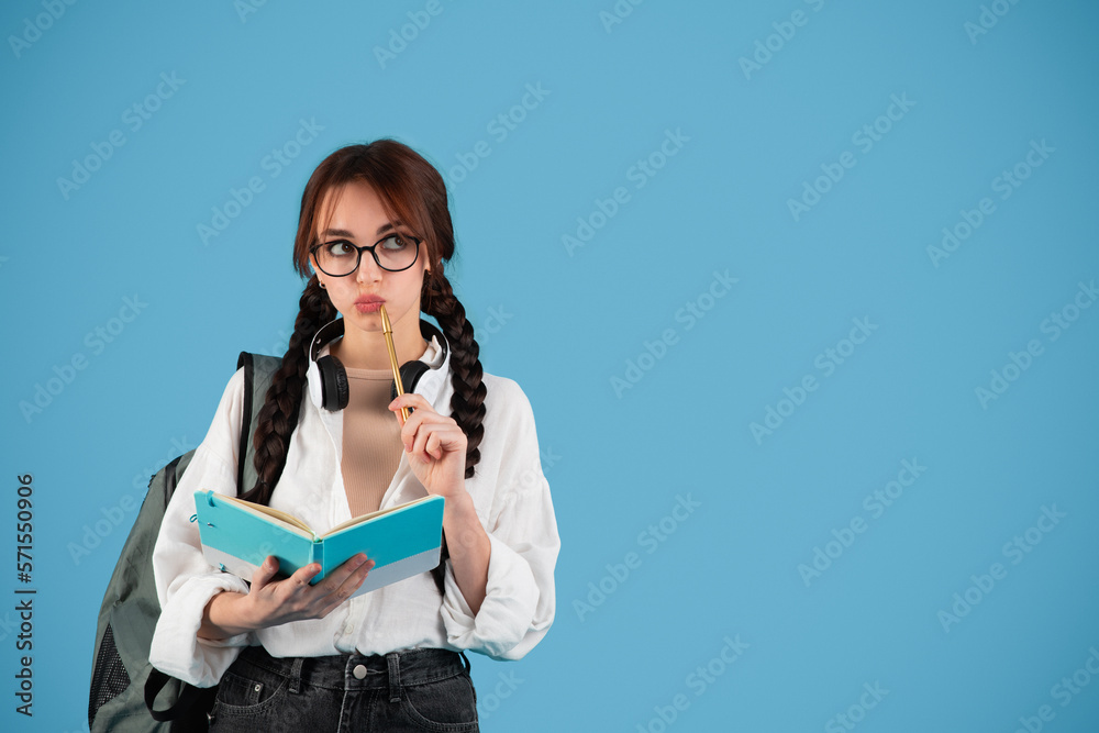 Pensive smart inspired caucasian teen girl with pigtails in glasses with headphones student with backpack Pensive smart inspired caucasian teen girl with pigtails in glasses with headphones student with backpack