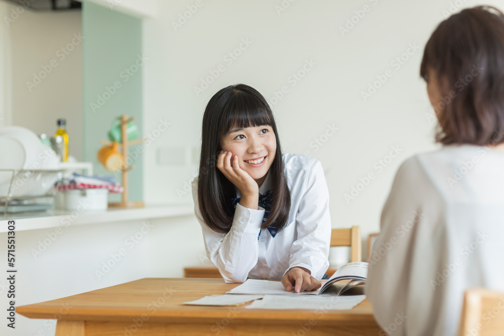 テーブルで資料を見ながら会話をする母娘 テーブルで資料を見ながら会話をする母娘