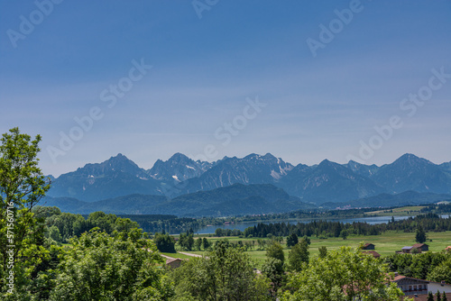 Green Bavarian Countryside with Distant Alpine Peaks Under Blue Sky