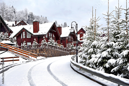 Wooden cottages holiday house in mountain holiday resort covered with fresh snow in winter.Beautiful winter street after snowfall.