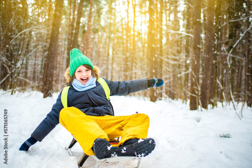 happy emotional screaming smiling boy sledding in winter snowy forest