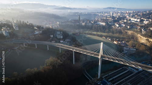 Grand pont suspendu au dessus d'une rivière, avec une ville et sa cathédrale en arrière plan
