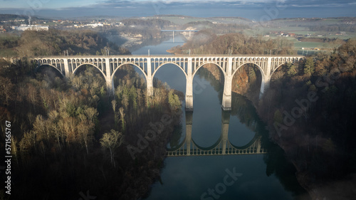 Viaduc pour le chemin de fer enjambant une rivière, avec son reflet dans l'eau photo