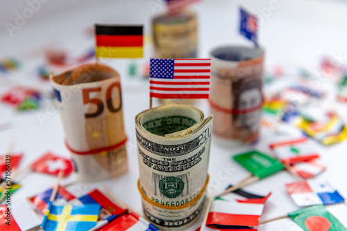 Obraz na plátně Rolled bundles of major currencies and country flags with the US Dollar and American flag in front