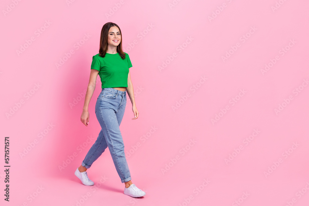 Full length photo of adorable sweet girl wear green crop top looking walking empty space isolated pink color background Full length photo of adorable sweet girl wear green crop top looking walking empty space isolated pink color background