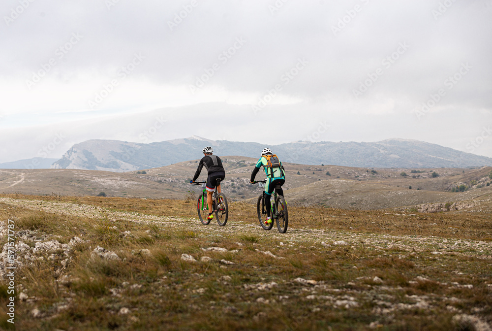 two male cyclists riding on mountain road on mountain bike