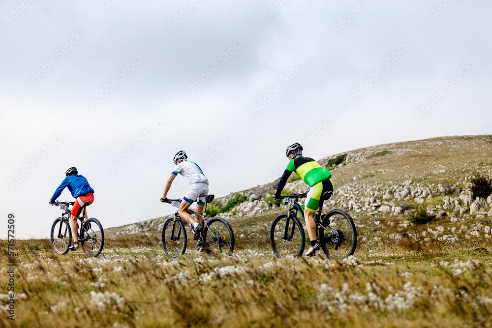 group athletes mountain bikers riding mountain trail race