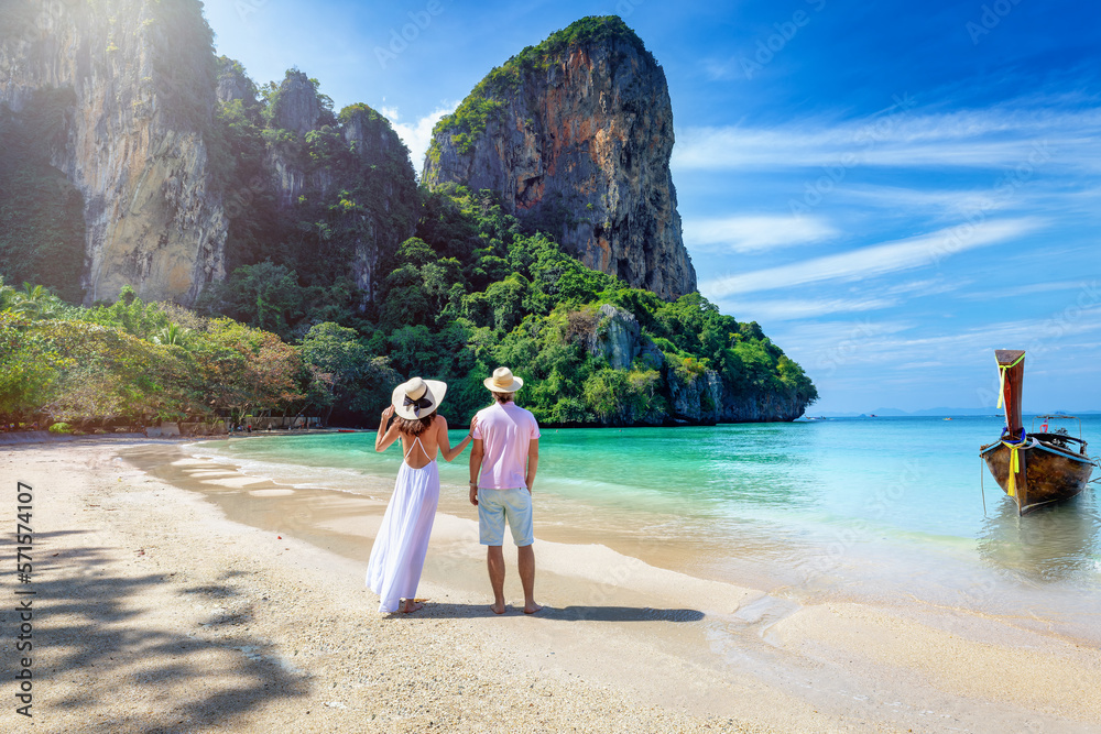 A happy couple stands on the beautiful beach of Railay, Krabi, Thailand, during their summer vacations