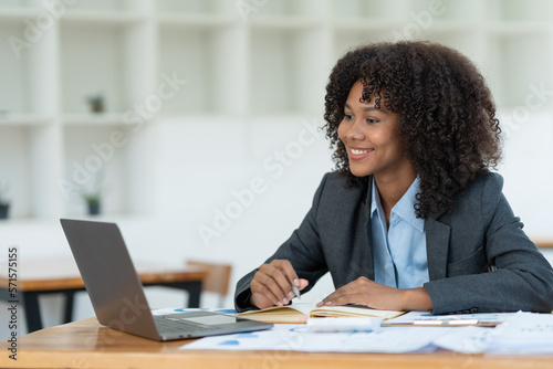 Positive successful african american woman, manager, CEO, sitting in the office at a laptop talking video call with client or employee discussing business strategy and ideas analyzed together
