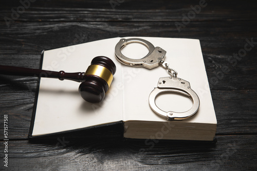 Metal handcuffs, book and judge gavel on the table.