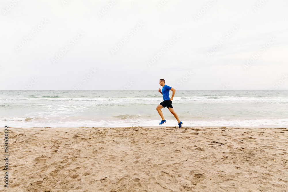 male jogger run sandy beach in background of sea and sky male jogger run sandy beach in background of sea and sky