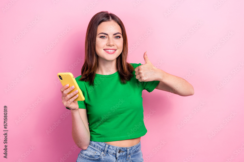Photo of cute lovely girl hold smart phone demonstrate thumb up approval isolated on pink color background Photo of cute lovely girl hold smart phone demonstrate thumb up approval isolated on pink color background