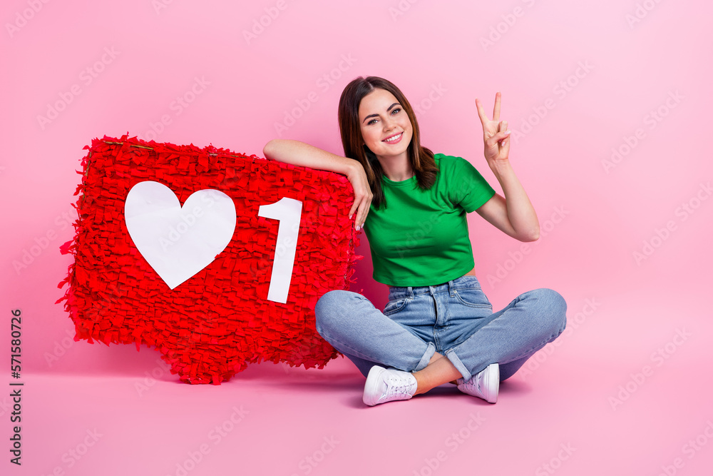 Full body photo of cheerful positive lady sit floor big like collage show v-sign isolated on pink color background Full body photo of cheerful positive lady sit floor big like collage show v-sign isolated on pink color background