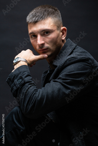 Young successful stylish man. Classical portrait of a businessman dressed in a jacket with a watch on his hand.