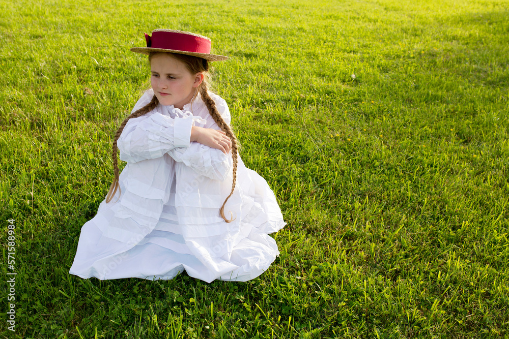 A cute girl with pigtails and a hat sits on a juicy light green grass. Cute little girl with hat on the grass A cute girl with pigtails and a hat sits on a juicy light green grass. Cute little girl with hat on the grass