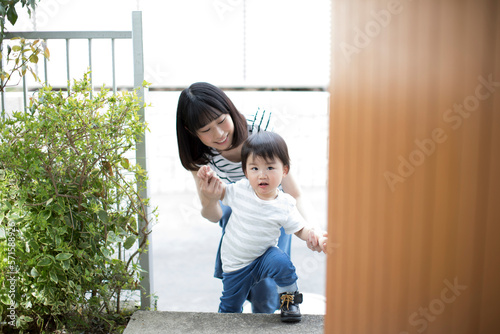 手をつないで家に入ろうとする幼児と母親