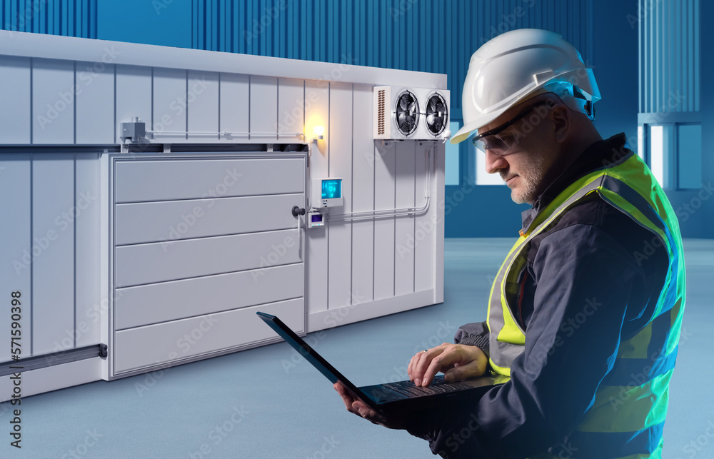 Foto de Engineer man near freezer. Worker controls warehouse
