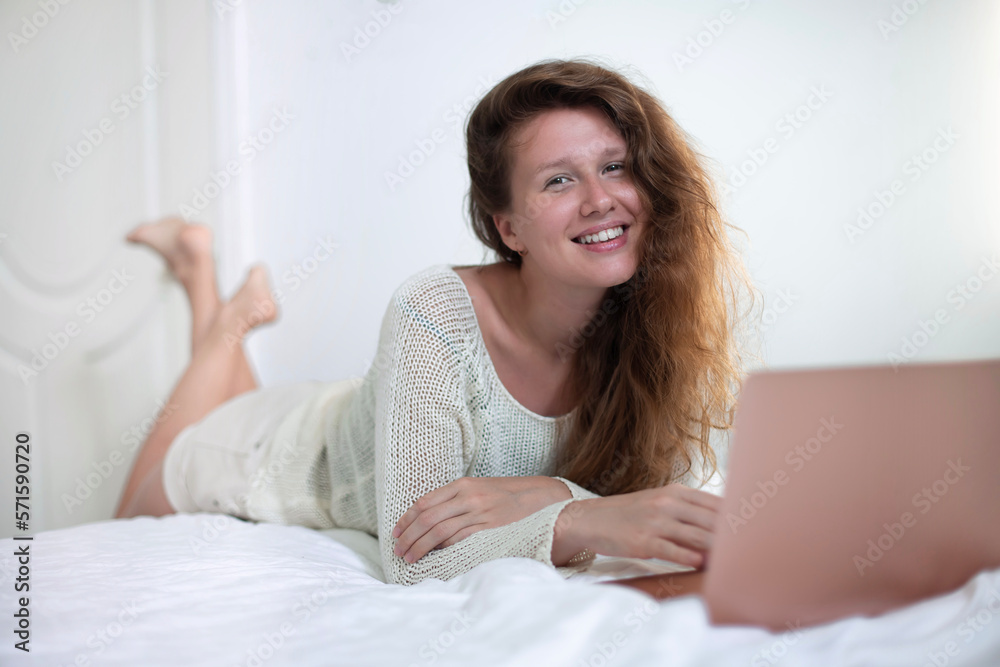 Happy joyful woman is using laptop computer at home on bed in bedroom and smiling Happy joyful woman is using laptop computer at home on bed in bedroom and smiling