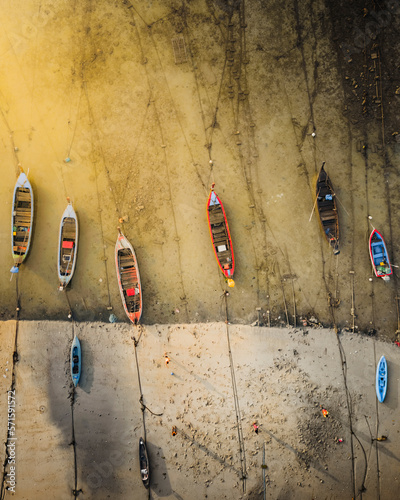 Aerial view of kids playing ball on the beach along the shore with boats docked at sunrise in Phuket, Thailand. photo