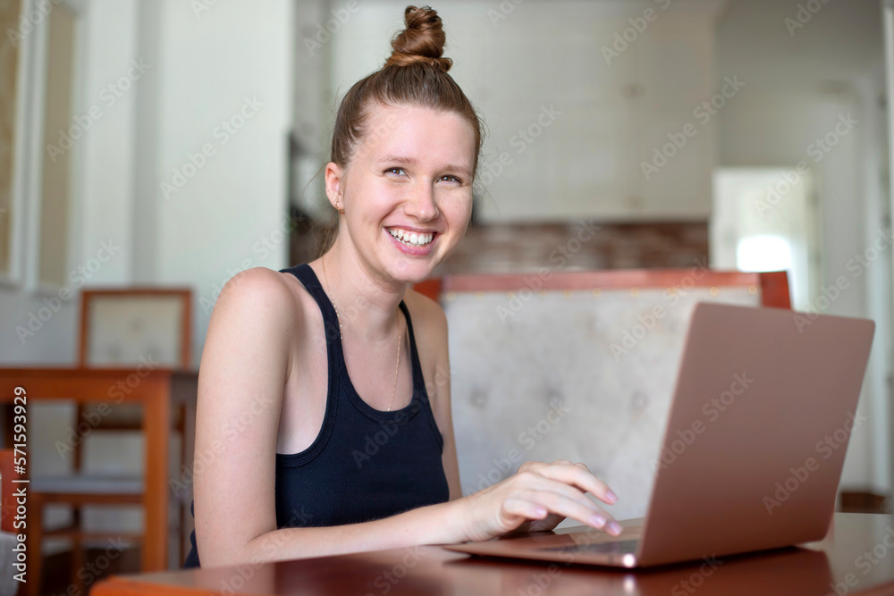 Young happy woman is using laptop computer at home in living room and smiling Young happy woman is using laptop computer at home in living room and smiling