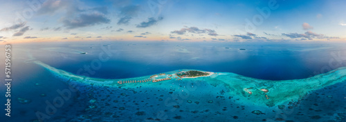 Panoramic aerial view of a luxury resort with boats anchored along the coast on Raa Atoll in the Laccadive Sea, Maldives archipelagos. photo