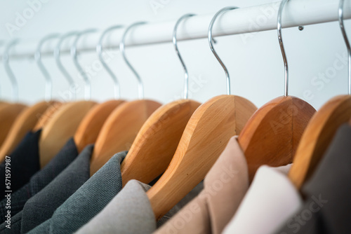 Fotografia Row of colorful cotton coat suits are hanged by wooden cloth hanger on the rail