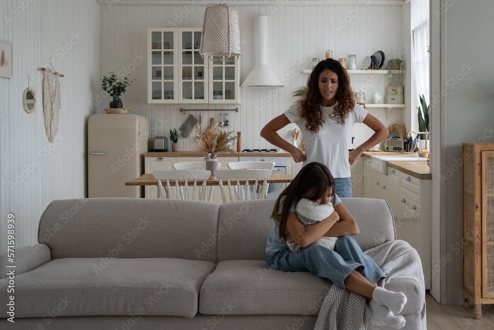 Strict mother scolding unhappy teenage daughter at home, mom lecturing