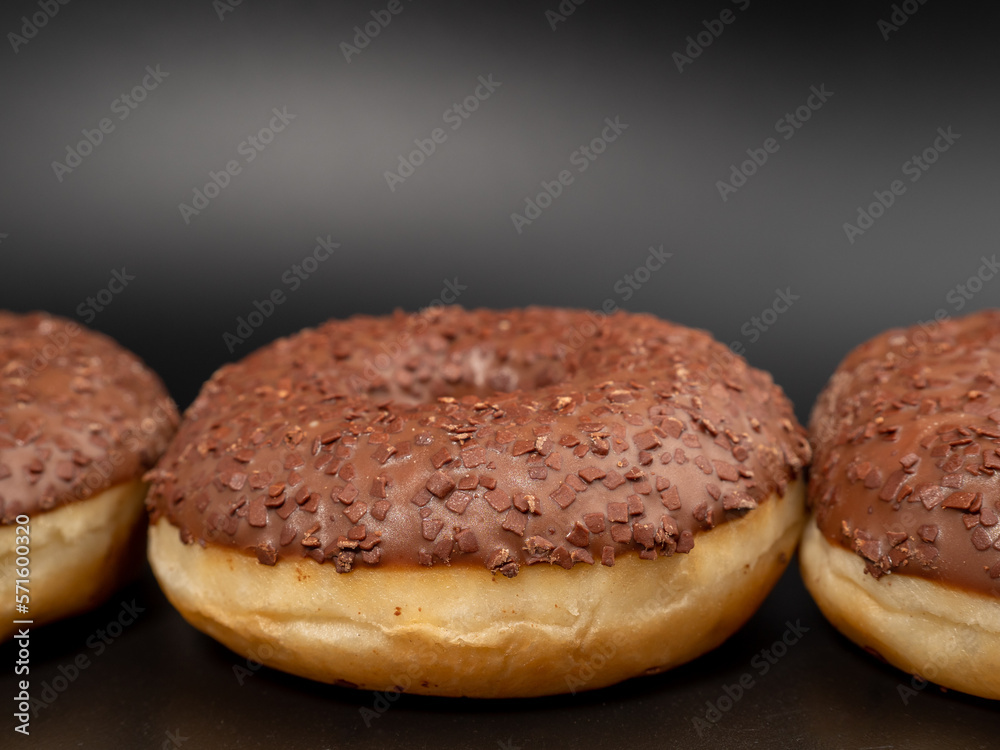 Chocolate donut with chocolate chips on a black background. close-up.