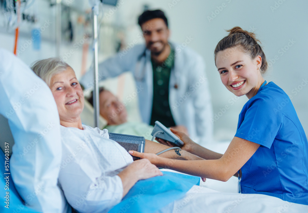 Obraz premium Young nurse chcecking blood presure to senior patient.