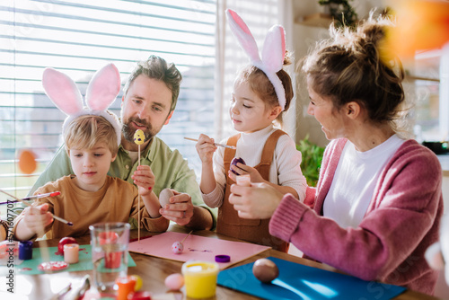 Canvas Print Happy family with little kids decorating easter eggs.