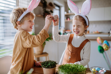 Little kids with bunny ears celebrating easter, playing easter game with egg.