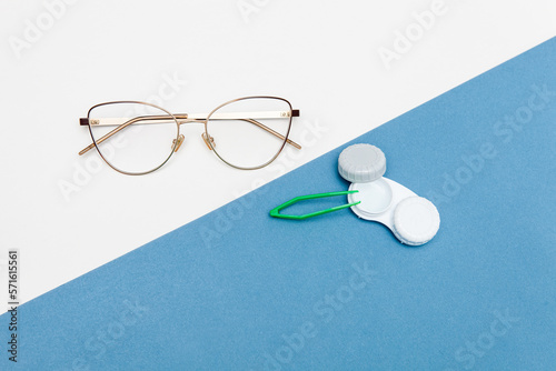 Contact lenses and glasses with a case, tweezers on a blue and white background
