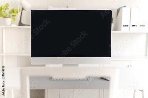 White table and chair with computer monitor and modern file cabinet in white home office © Naypong Studio