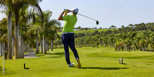 Golfer on a golf course, ready to tee off. Golfer with golf club hitting the ball for the perfect shot.